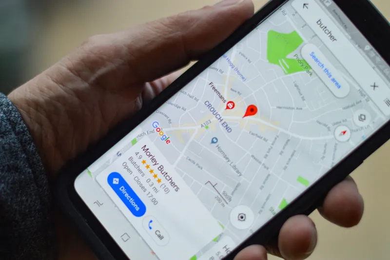 mano sujetando un movil con la pantalla mostrando un mapa de google con un marcador de ubicacion